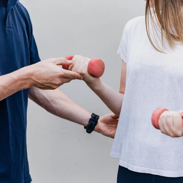 Exercise physiologist guiding a client through a dumbbell exercise